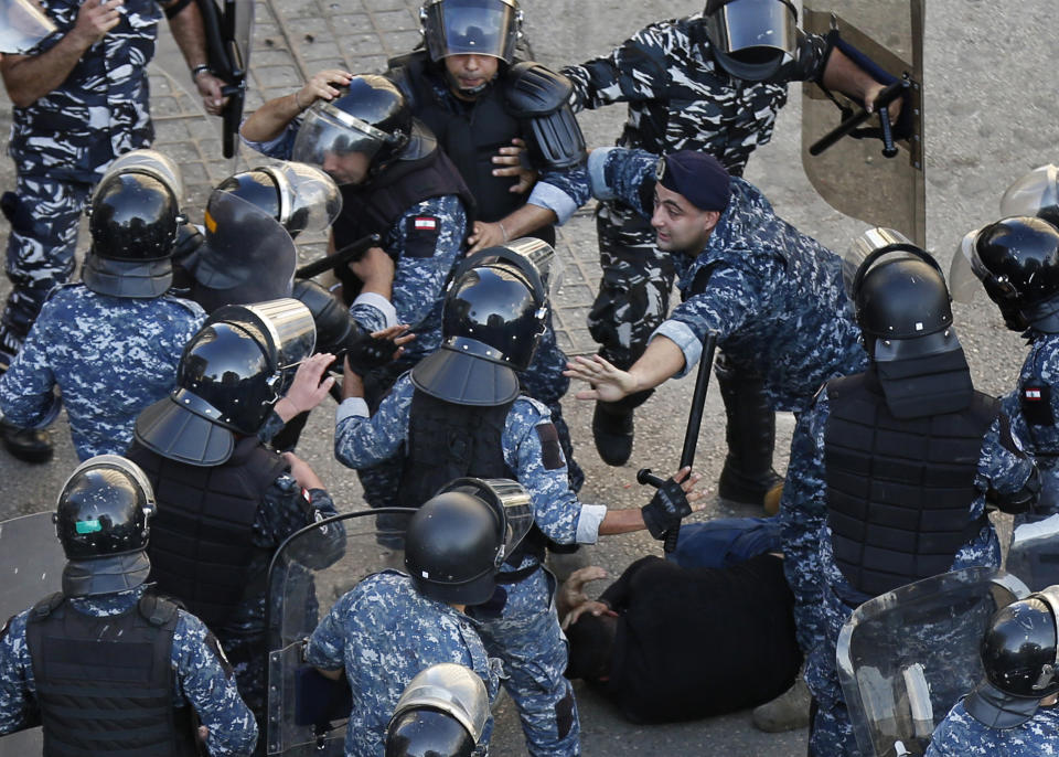 A riot police officer, center right, stops other policemen from beating a protester who lies on the ground, after clashes erupted between an anti-government protesters and Hezbollah supporters near the government palace, in Beirut, Lebanon, Tuesday, Oct. 29, 2019. Lebanon's prime minister resigned, bowing to one of the central demands of anti-government protests. (AP Photo/Hussein Malla)