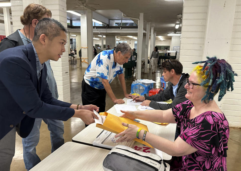 Democratic Party of Hawaii interim chair Adrian Tam places his presidential caucus ballot for counting in an envelope held by party volunteer Bonnie Fraser in Honolulu on Wednesday, March 6, 2024. (AP Photo/Audrey McAvoy)