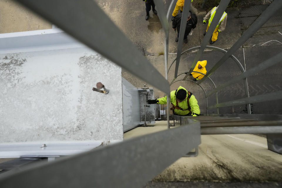 Delwyn Bodden, a worker for the Southeast Louisiana Flood Protection Authority-West climbs a ladder up a floodgate to lock it closed along the Harvey Canal, just outside the New Orleans city limits, in anticipation of Tropical Storm Francine, in Harvey, La., Tuesday, Sept. 10, 2024. (AP Photo/Gerald Herbert)