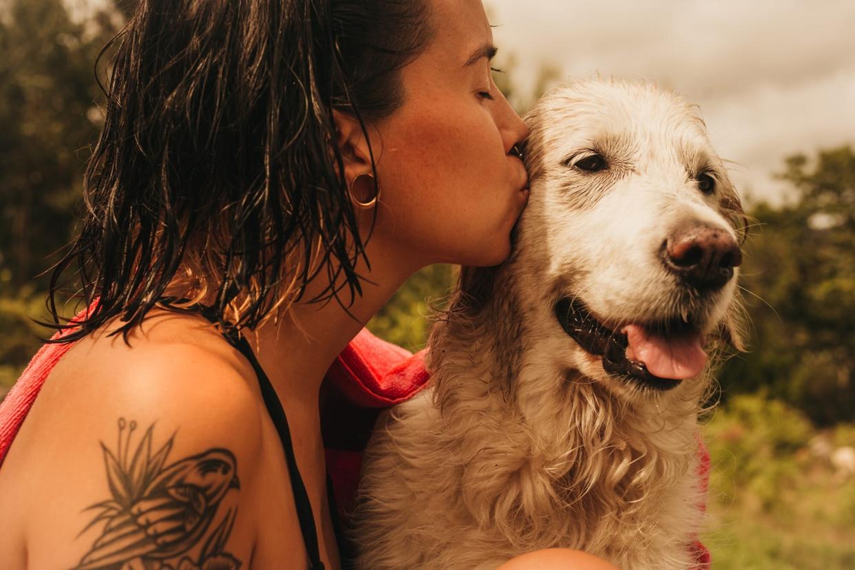 woman with wet hair giving her her dog with elbow dysplasia a kiss on the head