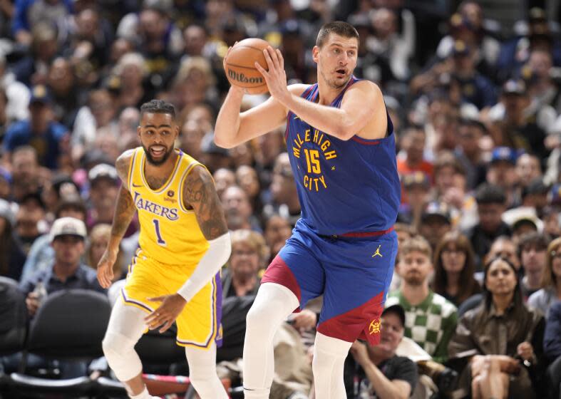 Denver Nuggets center Nikola Jokic collects the ball as Los Angeles Lakers guard D'Angelo Russell watches during the second half of an NBA basketball game Tuesday, Oct. 24, 2023, in Denver. (AP Photo/David Zalubowski)