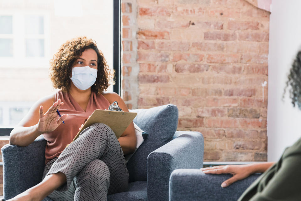 A mental health therapist talking to a patient with a mask on