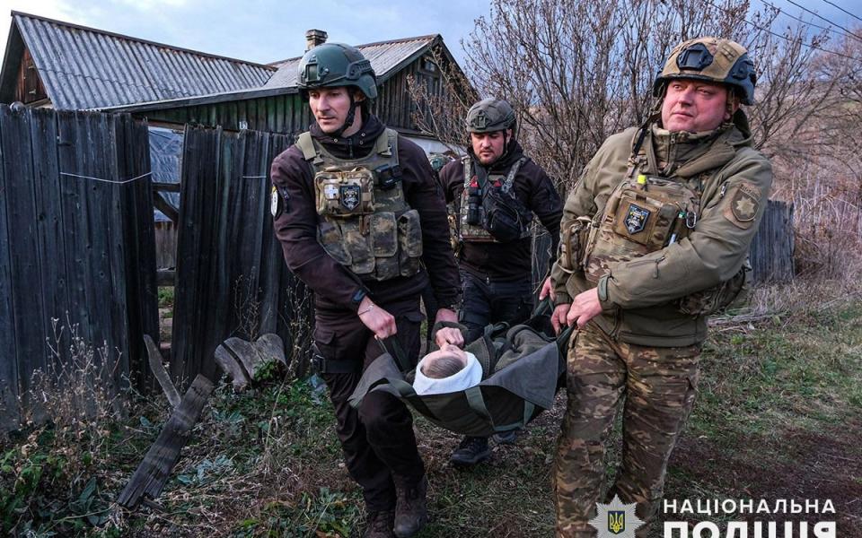 Ukrainian policemen carry an elderly woman out of Toretsk village in Donetsk