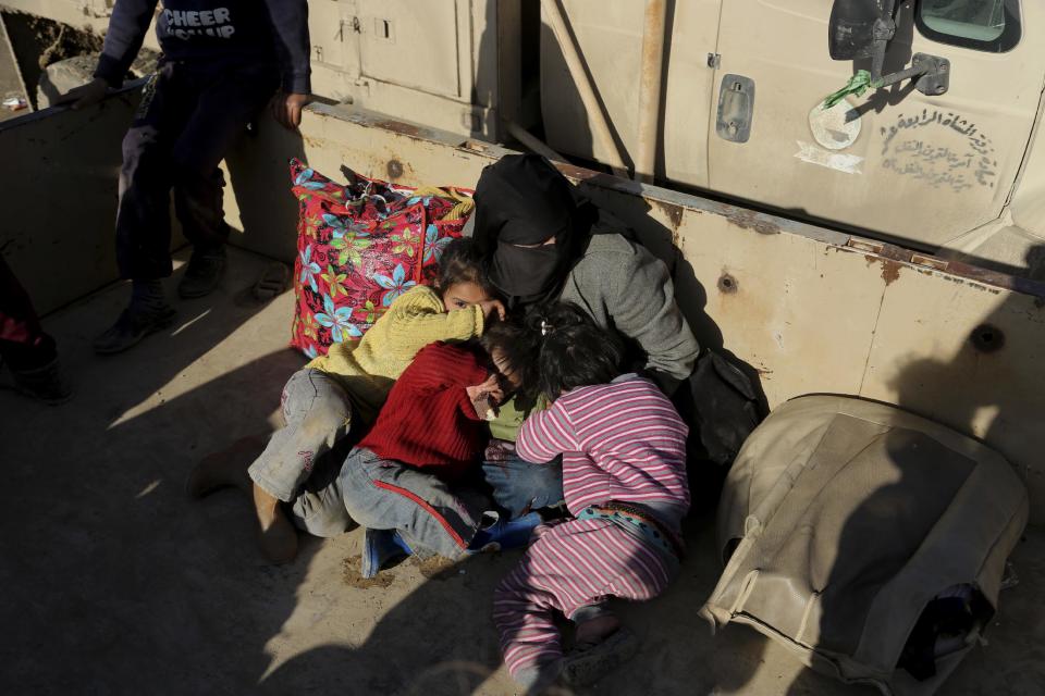 A mother and her daughters who fled fighting between Iraqi security forces and Islamic State militants, sit on an Iraqi Army truck at the gathering point as they wait to be taken for a camp for internally displaced people at Mosul, Iraq, Friday, Dec. 30, 2016. Iraq's special forces are continuing to push back Islamic State militants in the eastern sector of Mosul. (AP Photo/ Khalid Mohammed)