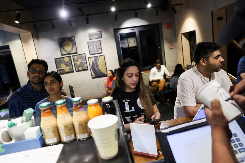 Customers stand next to a counter at a Starbucks' outlet at a market in New Delhi