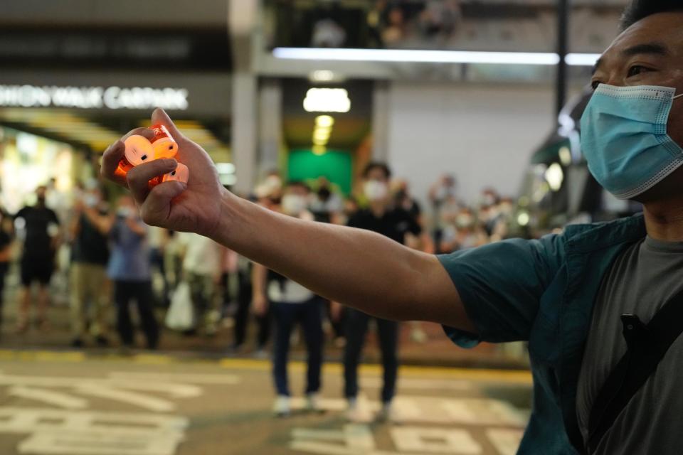 A police officer takes away LED candles which were displayed by a protester at a phone booth near the Hong Kong's Victoria Park, Saturday, June 4, 2022. Dozens of police patrolled Hong Kong’s Victoria Park on Saturday after authorities for a third consecutive year banned public commemoration of the anniversary of the deadly Tiananmen Square crackdown in 1989, with vigils overseas the only place marking the event. (AP Photo/Kin Cheung)