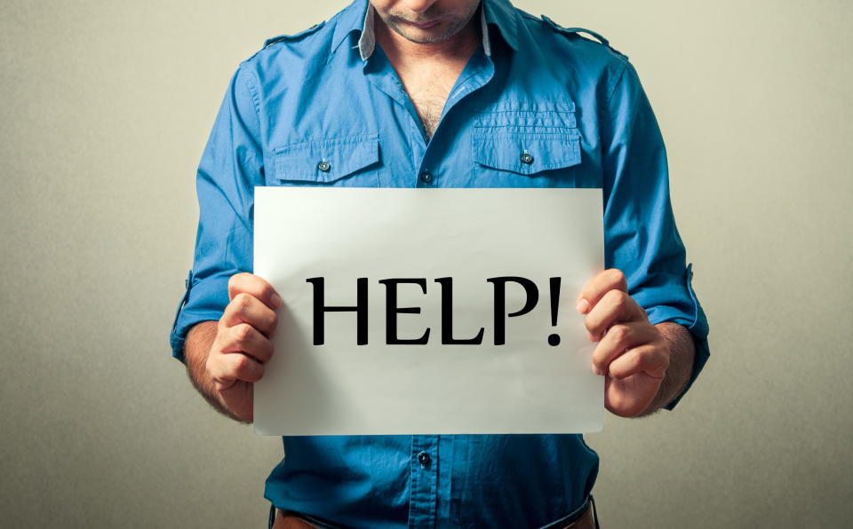 Midsection Of Depressed Mid Adult Man Holding Help Wanted Sign Against Gray Background