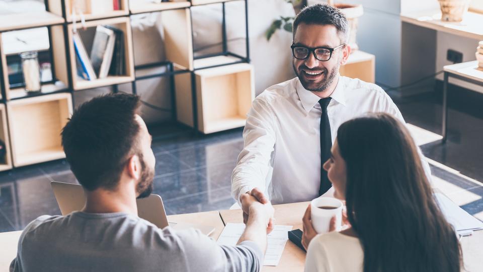 16 Most Important Assets That Will Increase Your Net Worth, Sealing a deal. Top view of two men sitting at the desk and shak