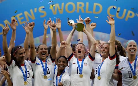 Megan Rapinoe lifts up the Women's World Cup trophy after the USA's victory over Holland - Credit: AP