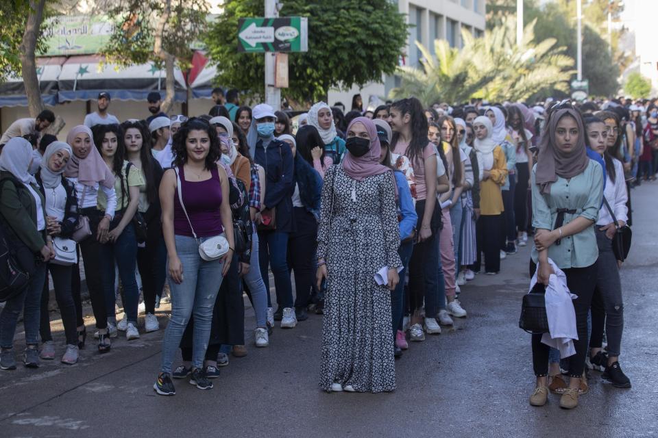 Syrian students attend to votes at a polling station during the Presidential elections in the Syrian capital Damascus, Syria, Wednesday, May 26, 2021. Syrians headed to polling stations early Wednesday to vote in the second presidential elections since the deadly conflict began in the Arab country. (AP Photo/Hassan Ammar)