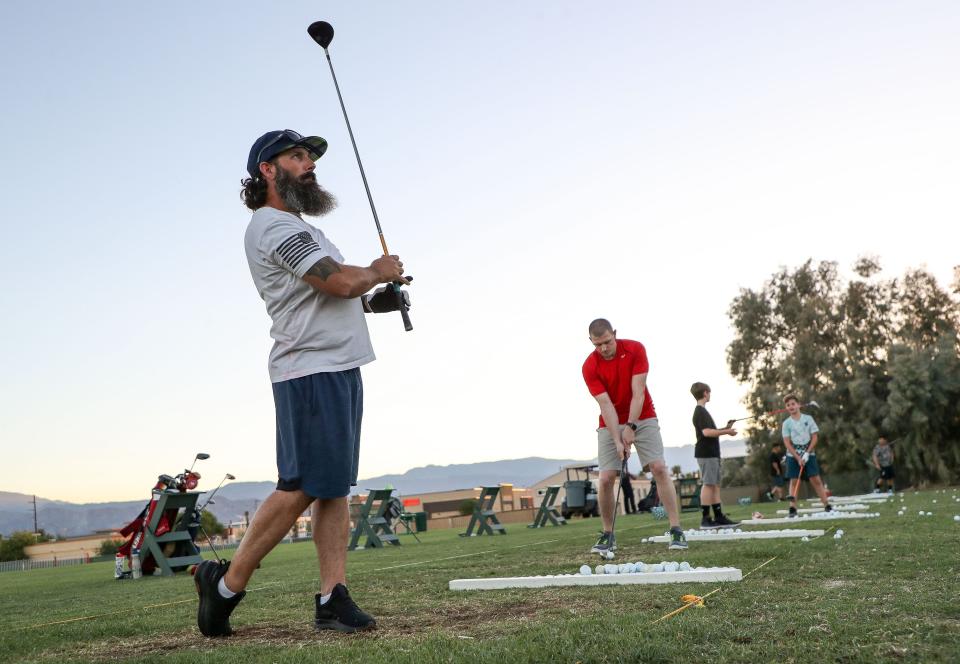 Chris Geraurd, left, hits golf balls on the range at The Lights at Indio Golf Course in Indio, Calif., August 4, 2023. 