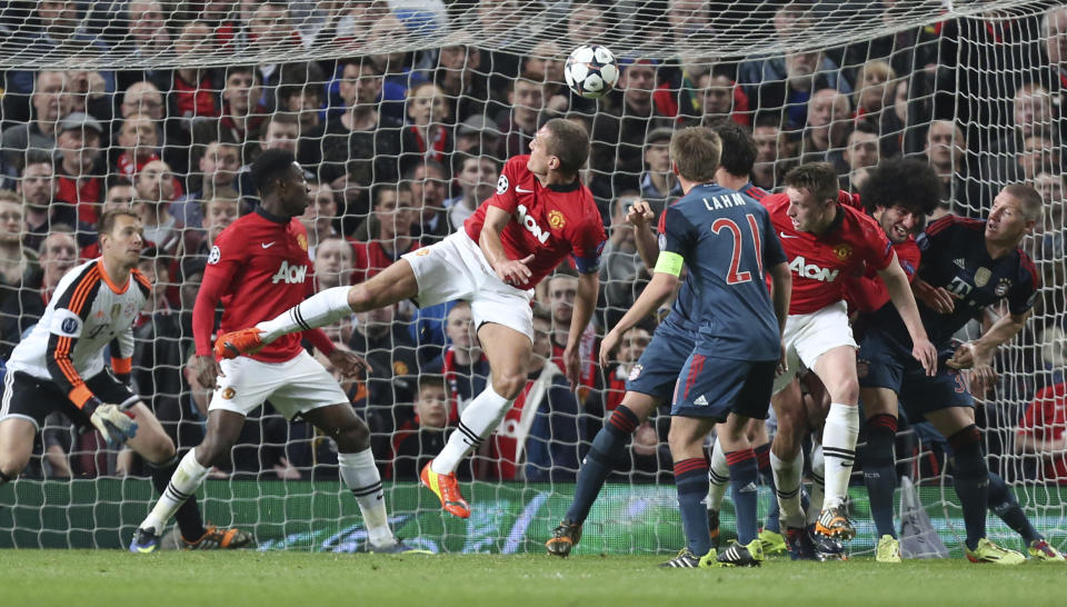 Manchester United's Nemanja Vidic, center, scores the opening goal during the Champions League quarterfinal first leg soccer match between Manchester United and Bayern Munich at Old Trafford Stadium, Manchester, England, Tuesday, April 1, 2014.(AP Photo/Jon Super)