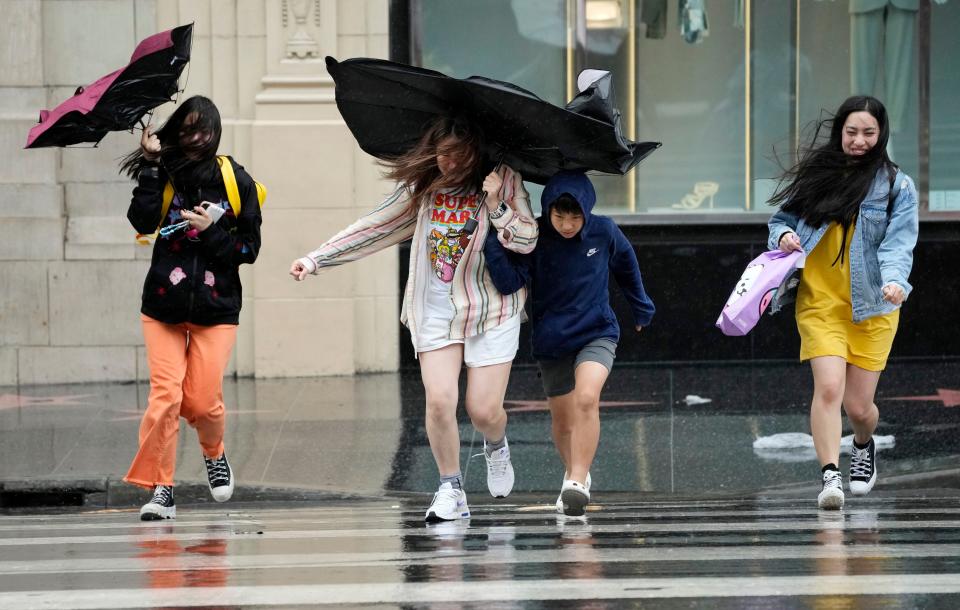 Pedestrians fight wind and rain as they cross Hollywood Boulevard during Tropical Storm Hilary, Sunday, Aug. 20, 2023, in Los Angeles. (AP Photo/Chris Pizzello)