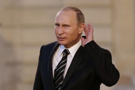 Russian President Vladimir Putin cups his ear to listen to a question as he departs after a summit on the Ukraine crisis at the Elysee Palace in Paris, France, October 2, 2015. REUTERS/Philippe Wojazer