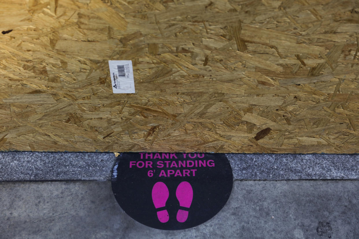 A sign advising to social distance is partially covered by a plywood panel protecting a restaurant from potential vandalism Wednesday, June 3, 2020, in downtown Los Angeles. (Jae C. Hong/AP)