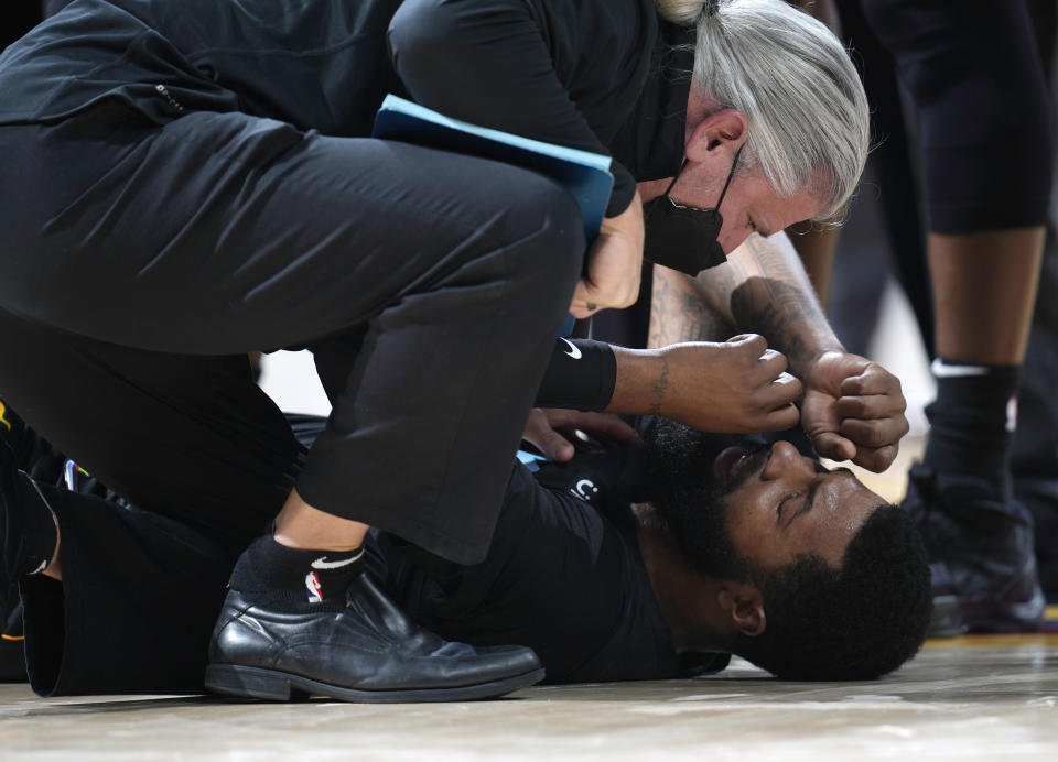 Miami Heat forward Markieff Morris, bottom, is attended to after being in an altercation with Denver Nuggets center Nikola Jokic in the second half of an NBA basketball game Monday, Nov. 8, 2021, in Denver. Morris walked off the court after being examined and Jokic was ejected. (AP Photo/David Zalubowski)