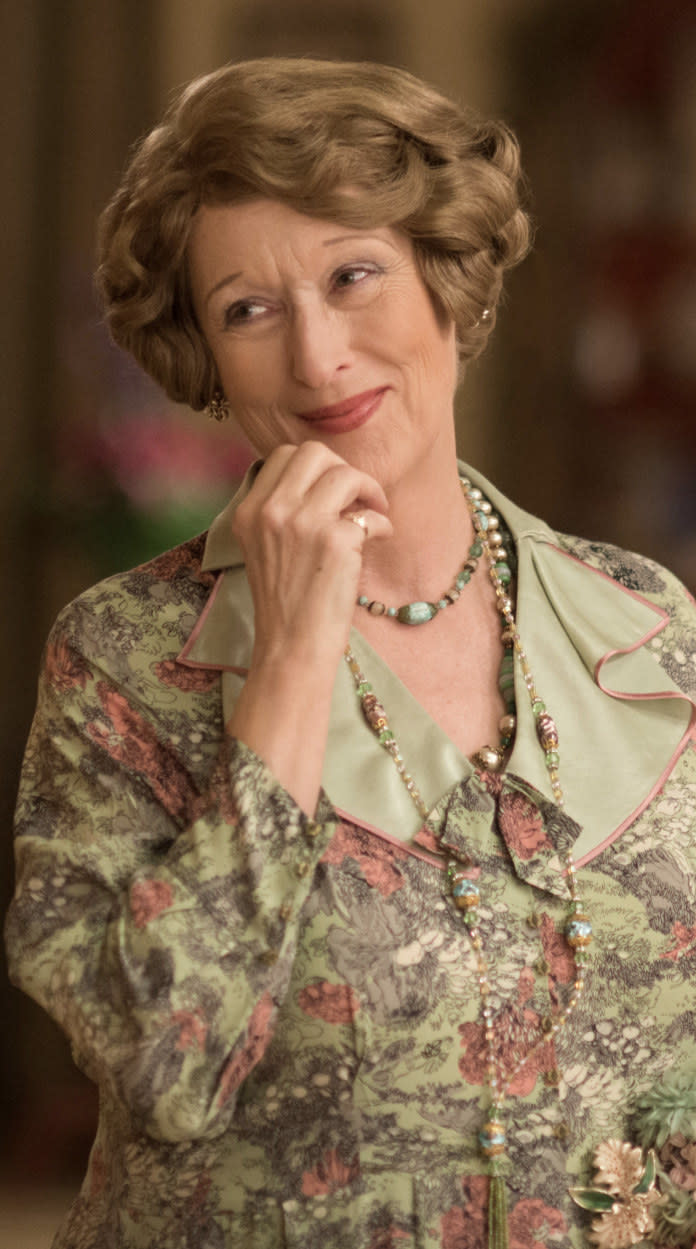 Streep smiling while wearing a floral dress and long necklace