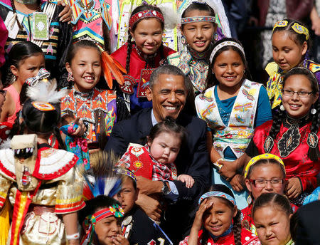 U.S. President Barack Obama holds a baby as he poses with children at the Cannon Ball Flag Day Celebration at the Cannon Ball Powwow Grounds on the Standing Rock Sioux Reservation in North Dakota, June 13, 2014. REUTERS/Larry Downing/File Photo
