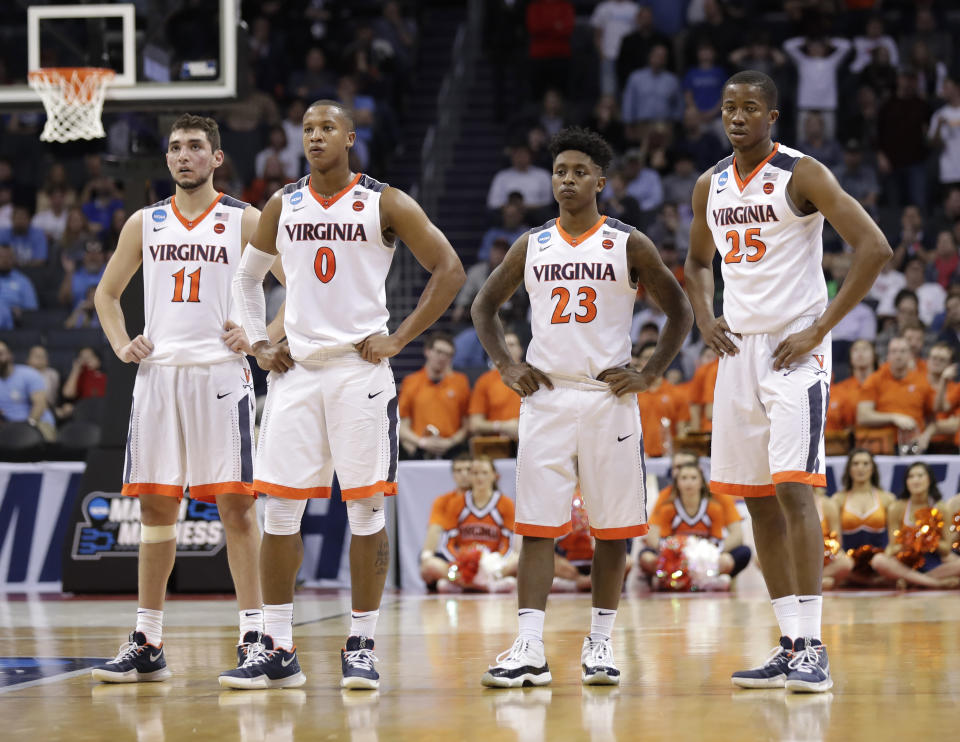 FILE - Virginia's Ty Jerome, Devon Hall, Nigel Johnson and Mamadi Diakite, from left, watch as a UMBC player shoots free throws during the second half of a first-round game in the NCAA men's college basketball tournament in Charlotte, N.C., March 16, 2018. Virginia fell to UMBC in the first-ever 16-vs-1 upset in 2018. Yet those Cavaliers regrouped to win the national championship the following season. (AP Photo/Gerry Broome, File)