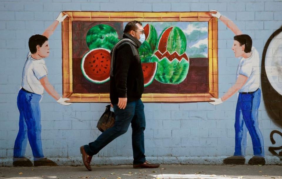 Hombre con mascarilla pasando por delante de un mural en Ciudad de México el 20 de abril de 2020.