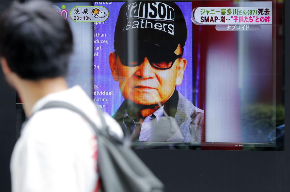 A passer-by watches a TV news reporting Johnny Kitagawa's passing away in Tokyo Wednesday, July 10, 2019. Kitagawa, who produced famous boybands including Arashi and SMAP and was a kingpin of Japan’s entertainment industry for more than half a century, has died Tuesday from a subarachnoid hemorrhage at a Tokyo hospital. He was 87. (Kyodo News via AP)