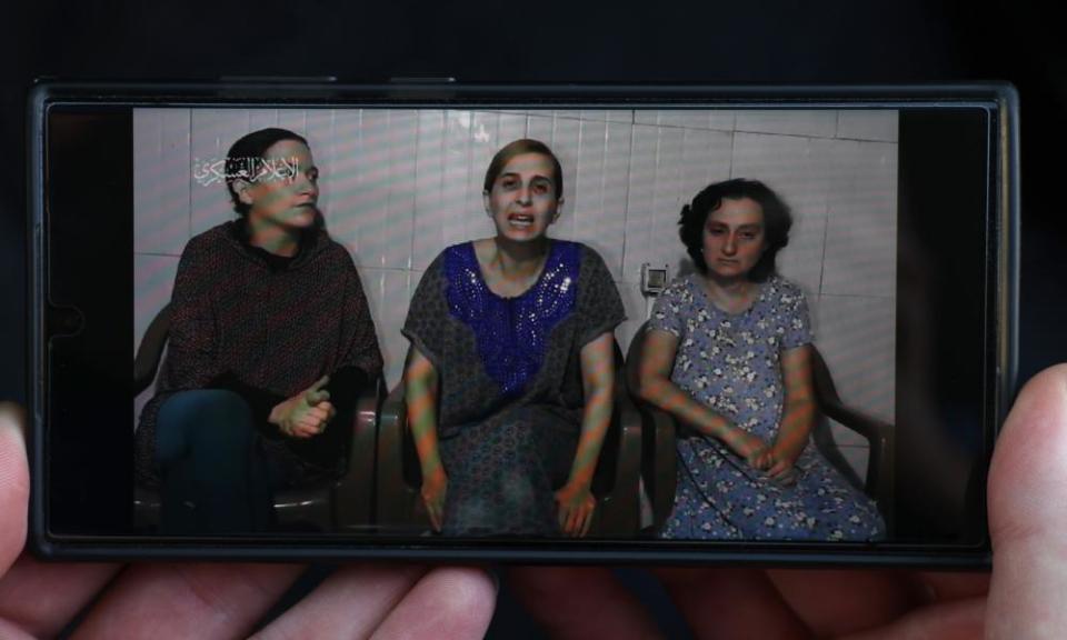 A phone displays footage released by Hamas showing three hostages (left to right) Rimon Kirsht, Danielle Aloni and Elena Trupanov.