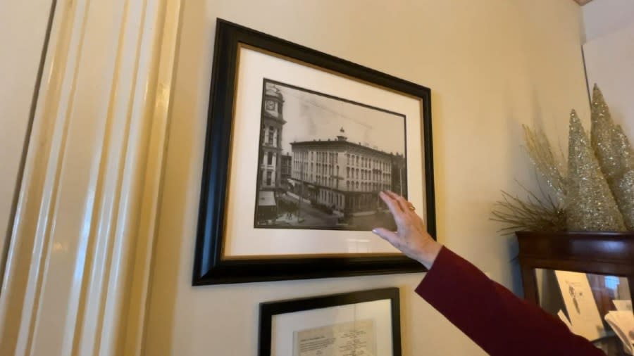 Carol Dodge points to a black-and-white photo of Martin Sweet's bank that is hanging on a wall.