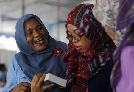 Salawati (L), an Acehnese survivor of the 2004 Indian Ocean tsunami, talks to her customers in Jakarta November 29, 2014. REUTERS/Pius Erlangga