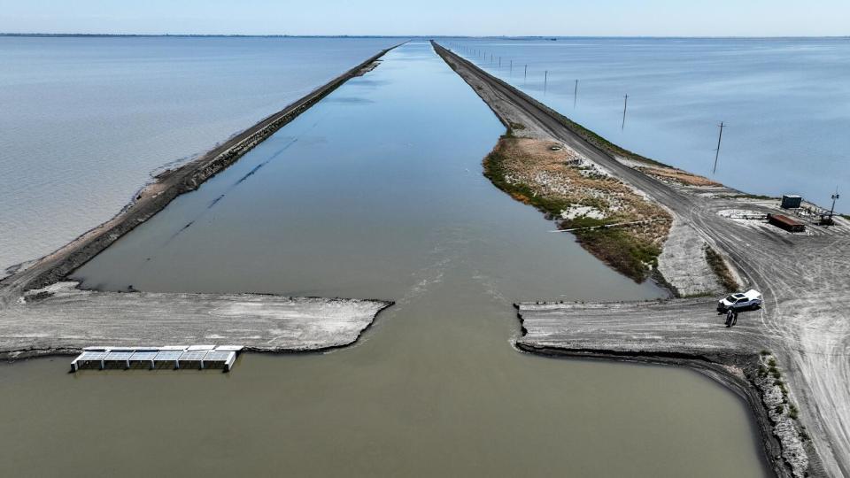 Floodwaters reach to the horizon past a breeched levee.