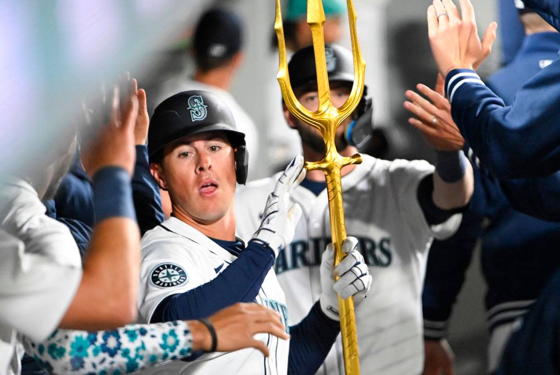 Seattle Mariners left fielder Dylan Moore (25) celebrates a two-run homer against the Boston Red Sox with the trident in the dugout during the seventh inning of the opening day game at T-Mobile Park, on Thursday, March 28, 2024, in Seattle, Wash. Brian Hayes/bhayes@thenewstribune.com