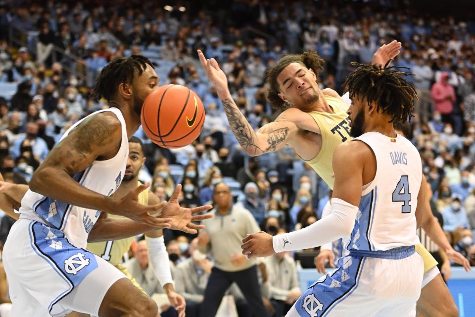 North Carolina’s Leaky Black, left, and RJ Davis, right, and Georgia Tech’s Jordan Usher try to corral a loose ball Saturday night.