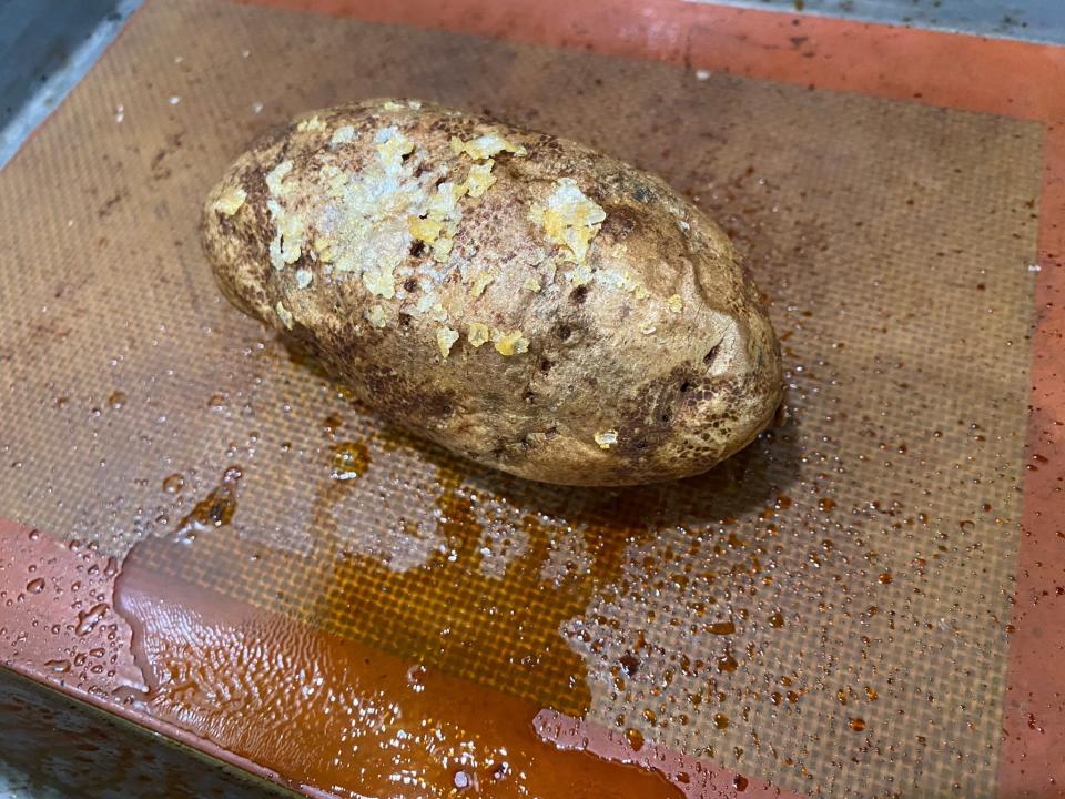 baked potato on a baking tray with some liquid coming out of it