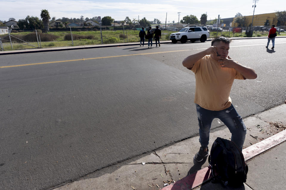 A migrant from Ecuador shaves as he arrives at a bus stop after leaving a processing facility, Friday, Feb. 23, 2024, in San Diego. Hundreds of migrants were dropped off Friday at a sidewalk bus stop amid office parks in San Diego with notices to appear in immigration court after local government funding for a reception center ran out of money sooner than expected. (AP Photo/Gregory Bull)