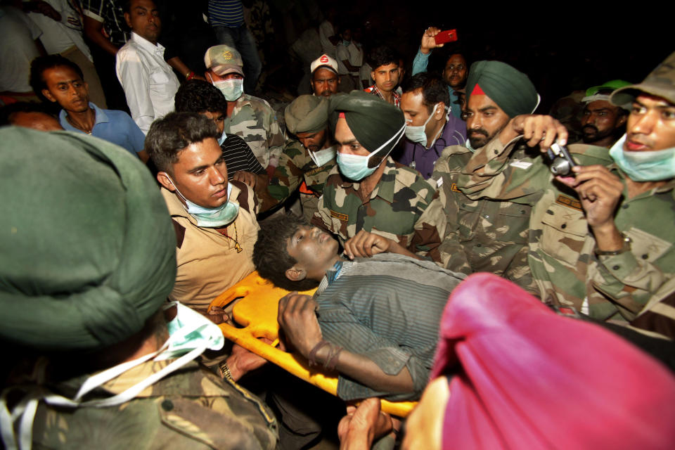 Rescue workers carry Indian survivor Sandeep out from the rubble of a factory that collapsed in Jalandhar, India, Wednesday, April 18, 2012. Rescue work continues at the site of a three-story blanket factory that collapsed in northern India close to midnight Sunday, killing at least five people. (AP Photo/Channi Anand)