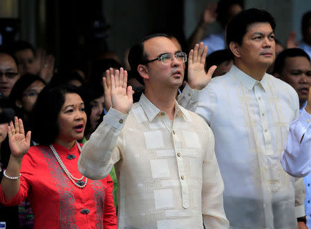 The newly installed Philippines' Foreign Secretary Alan Peter Cayetano (C) pledges his allegiance to the country's flag, during a flag raising at the Department of Foreign Affairs headquarters in Pasay City, Metro Manila, Philippines May 22, 2017. REUTERS/Romeo Ranoco