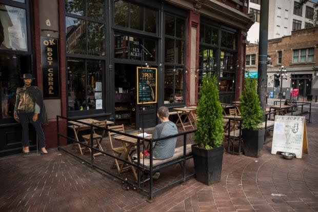 A patron sits on a patio of a restaurant in Vancouver's Gastown a year ago. Restaurant owners in the city won't have to pay for permits for their patios this year.  (Ben Nelms/CBC - image credit)