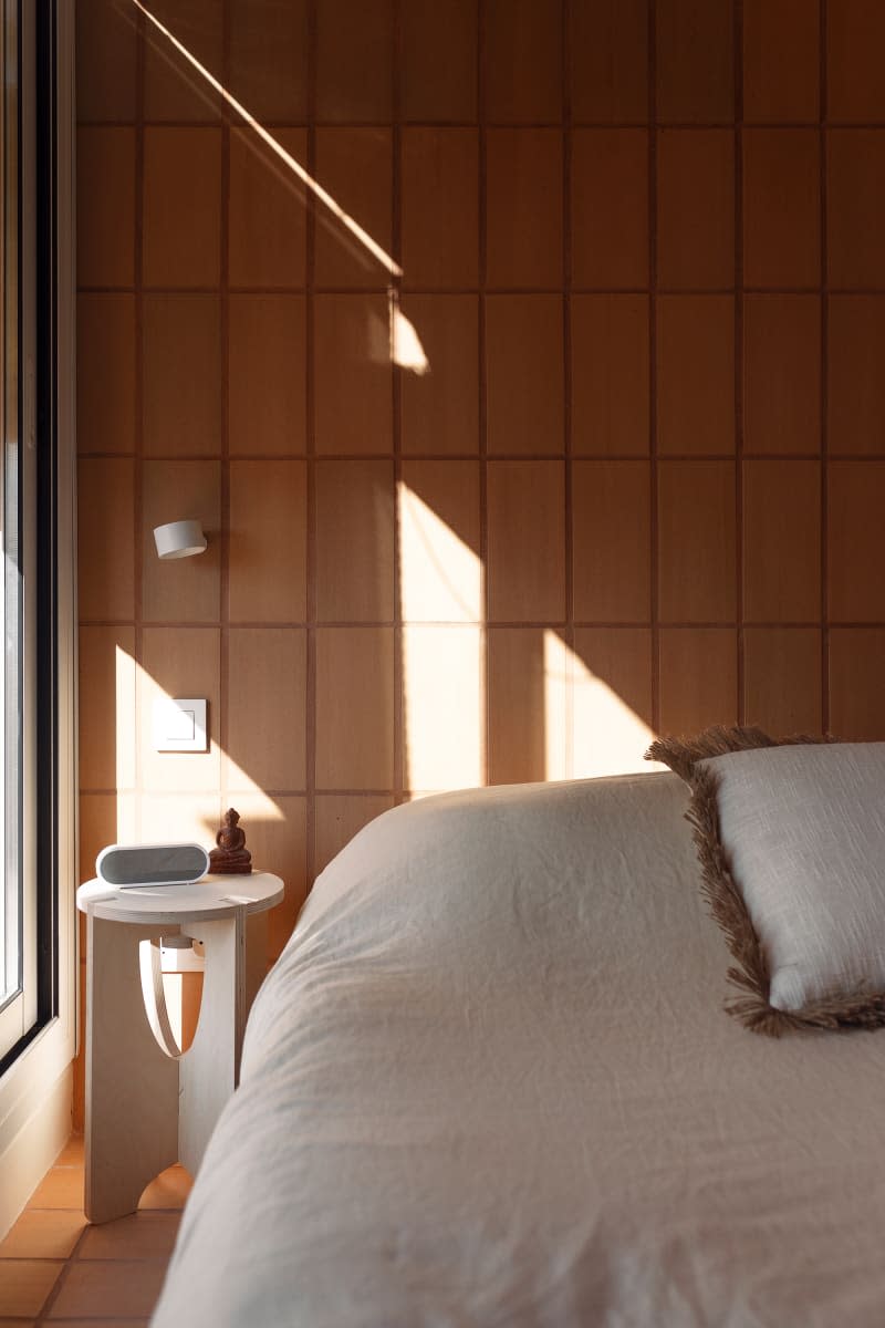 Bedside table in front of brick wall in bedroom.