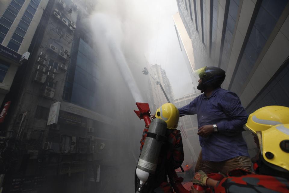 A commuter watches firefighters work to douse a fire in a multi-storied office building in Dhaka, Bangladesh, March 28, 2019. (AP Photo/Mahmud Hossain Opu)