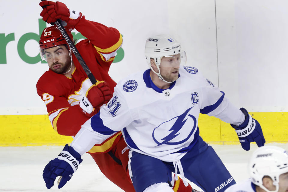 Tampa Bay Lightning center Steven Stamkos (91) tries to defend against Calgary Flames center Dillon Dube (29) after losing his stick during the first period of an NHL hockey game Saturday, Dec. 16, 2023, in Calgary, Alberta. (Larry MacDougal/The Canadian Press via AP)