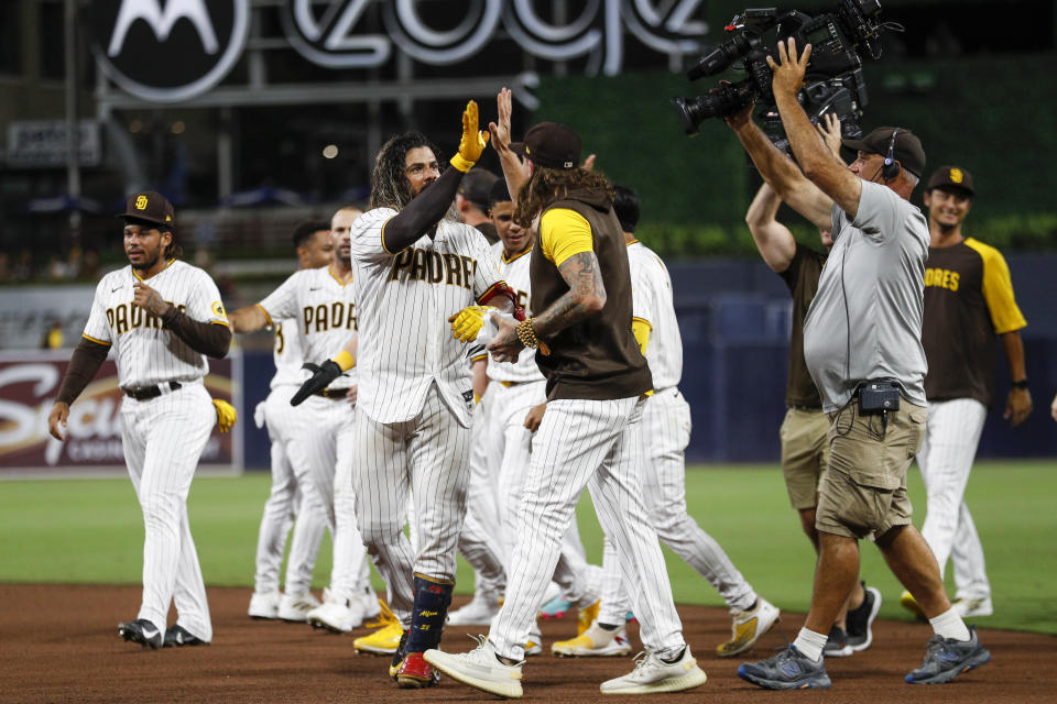 San Diego Padres' Jorge Alfaro, front left, high-fives with Mike Clevinger after hitting a two-run single against the Arizona Diamondbacks during the ninth inning of a baseball game Tuesday, Sept. 6, 2022, in San Diego. (AP Photo/Brandon Sloter)