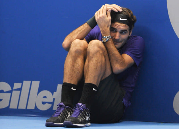 Swiss tennis player Roger Federer jokes to hide from a serve of French Jo-Wilfried Tsonga as he asks a ballboy to play for him during an exhibition match held at the Ibirapuera Gymnasium in Sao Paulo, Brazil, on December 8, 2012. AFP PHOTO/Yasuyoshi CHIBA