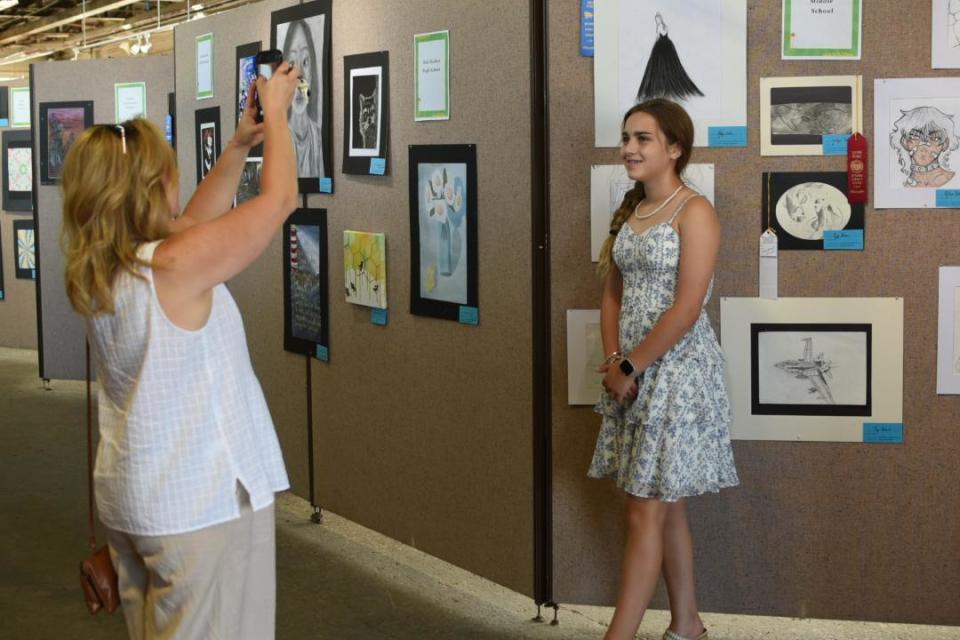Amy Simkus takes a picture of her daughter Adelyn Simkus, 12, with her artwork on display at The Arts Garage (TAG) in Port Clinton. The Greater Port Clinton Area Arts Council and North Point Educational Service Center teamed to exhibit the Ottawa County Jr. Fair Art Show at TAG this month.