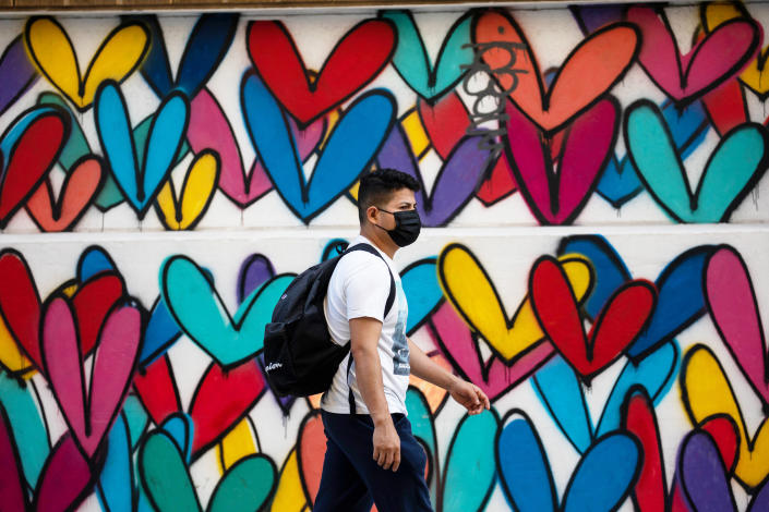 A man wearing a face mask passes a mural of heart-shaped patterns in the Brooklyn borough of New York, the United States, Oct. 2, 2021. (Michael Nagle/Xinhua via Getty Images)