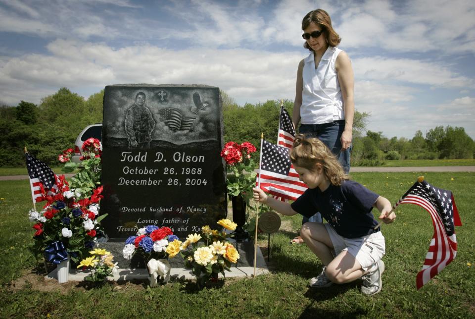 Nancy Olson of Loyal and her daughter, Kasey, 6, place flags at the grave of husband and father Todd Olson the day after the headstone was delivered. Todd Olson was a member of the 1st Battalion, 128th Infantry. He died in Iraq on Dec. 26, 2004.