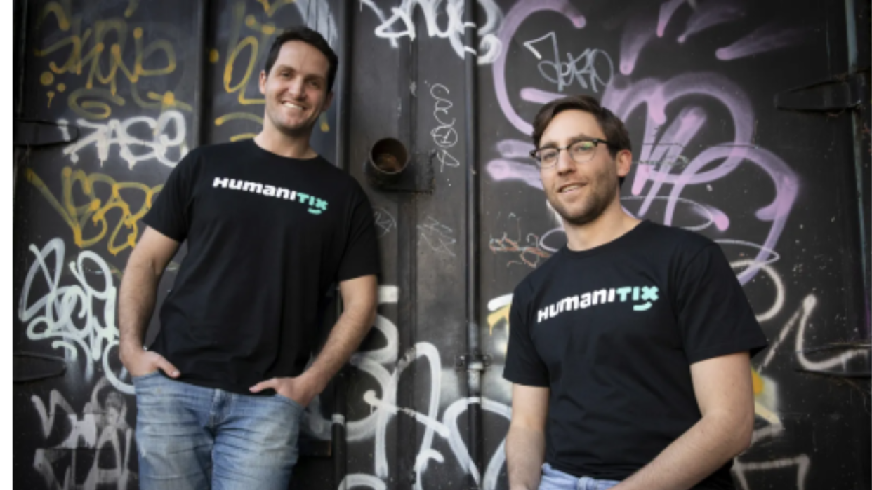 Adam and Josh post in front of a wall smiling that is covered in graffiti