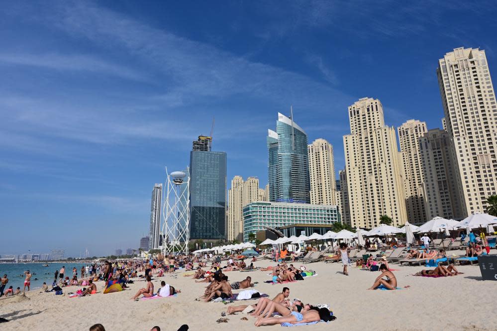 People on a beach overlooked by skyscrapers