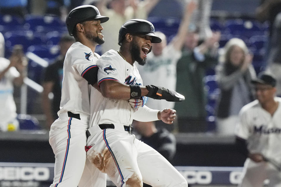 Miami Marlins' Otto Lopez lifts Bryan De La Cruz, after De La Cruz scored the winning run during the 10 inning of a baseball game against the Colorado Rockies, Tuesday, April 30, 2024, in Miami. The Marlins defeated the Rockies 7-6. (AP Photo/Marta Lavandier)