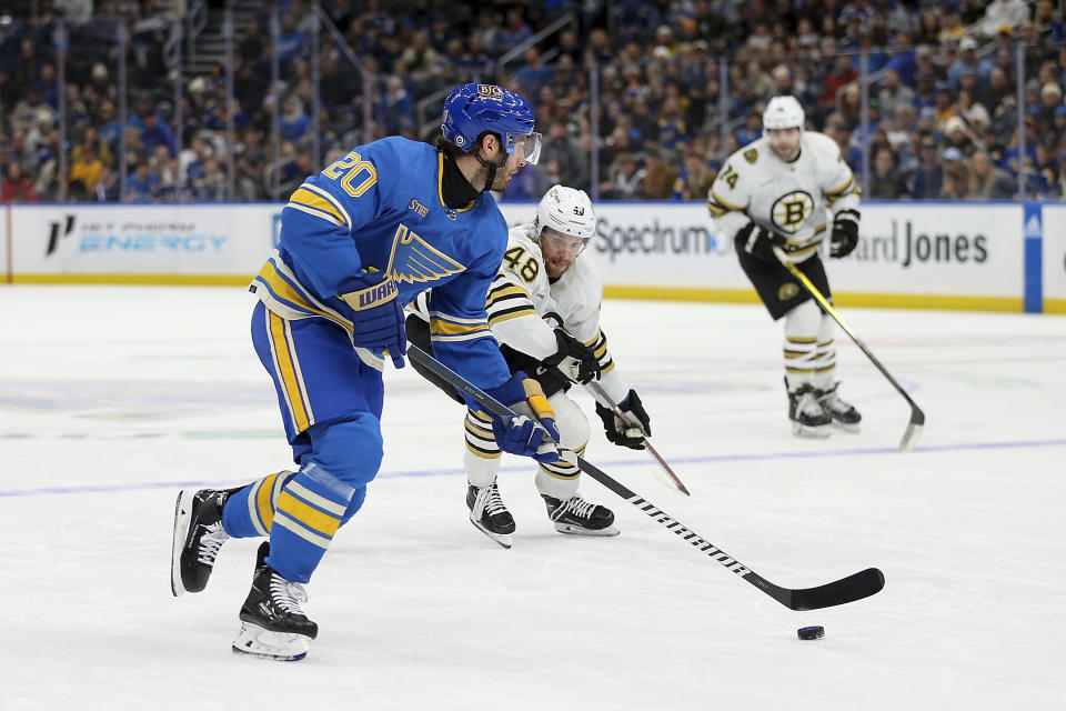St. Louis Blues' Brandon Saad (20) controls the puck while under pressure from Boston Bruins' Matt Grzelcyk (48) during the second period of an NHL hockey game Saturday, Jan. 13, 2023, in St. Louis. (AP Photo/Scott Kane)