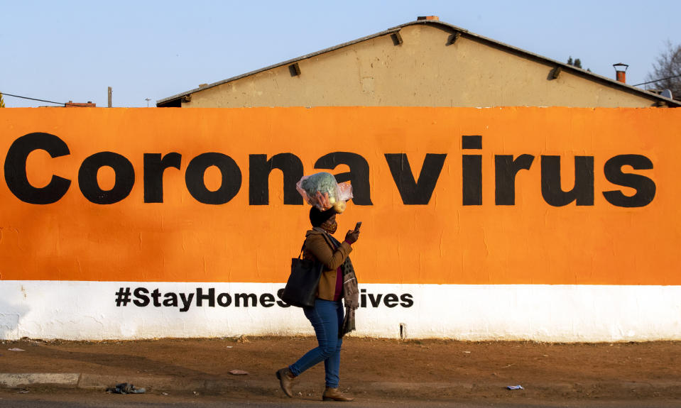 FILE - In this Friday June 19, 2020, a woman wearing a face mask passes a coronavirus billboard carrying a message in a bid to prevent the spread of the virus. South Africa's Health Minister Zwelini Mkhize said Sunday June 28, 2020 the country's current surge of COVID-19 cases is expected to dramatically increase in the coming weeks and press the country's hospitals to the limit. (AP Photo/Themba Hadebe/File)