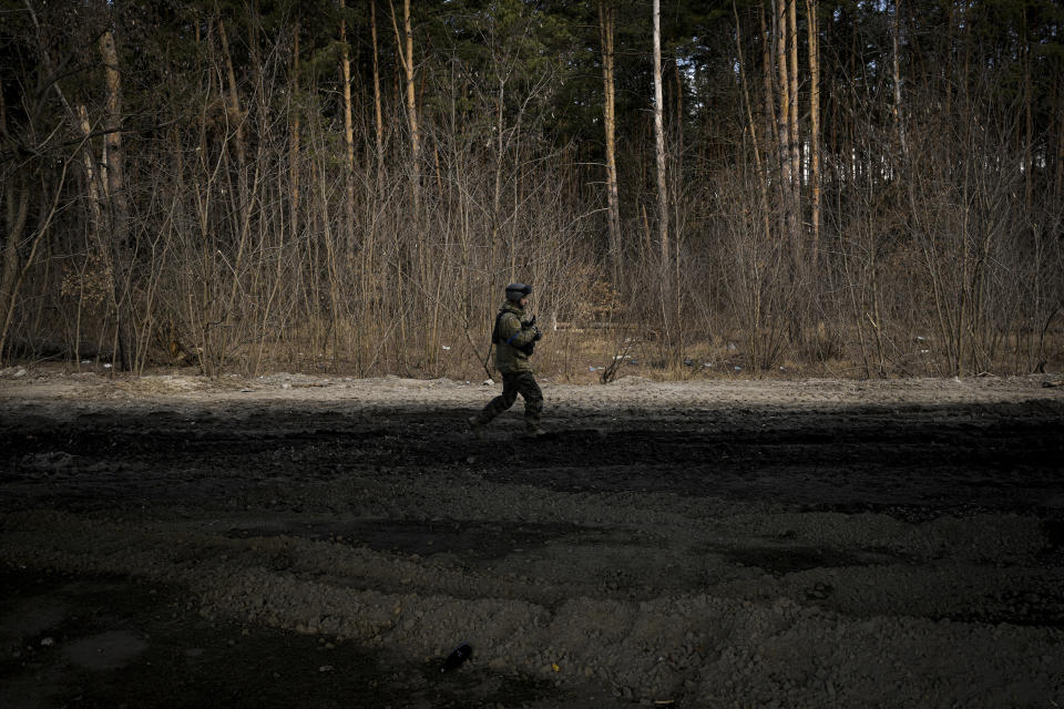 A Ukrainian serviceman walks on the edge of a forest in Stoyanka, Ukraine, Sunday, March 27, 2022. Ukrainian President Volodymyr Zelenskyy accused the West of lacking courage as his country fights to stave off Russia's invading troops, making an exasperated plea for fighter jets and tanks to sustain a defense in a conflict that has ground into a war of attrition. (AP Photo/Vadim Ghirda)